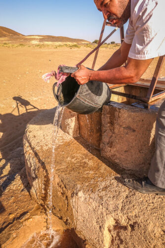 Pouring water from nomad well Iriki Lake Sahara Morocco